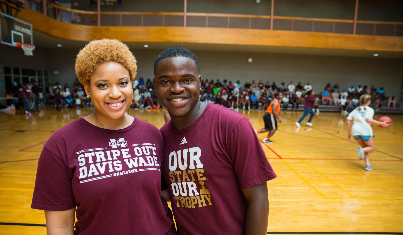 Dawg Daze volunteers pose in front of basketball tournament at the Sanderson Center