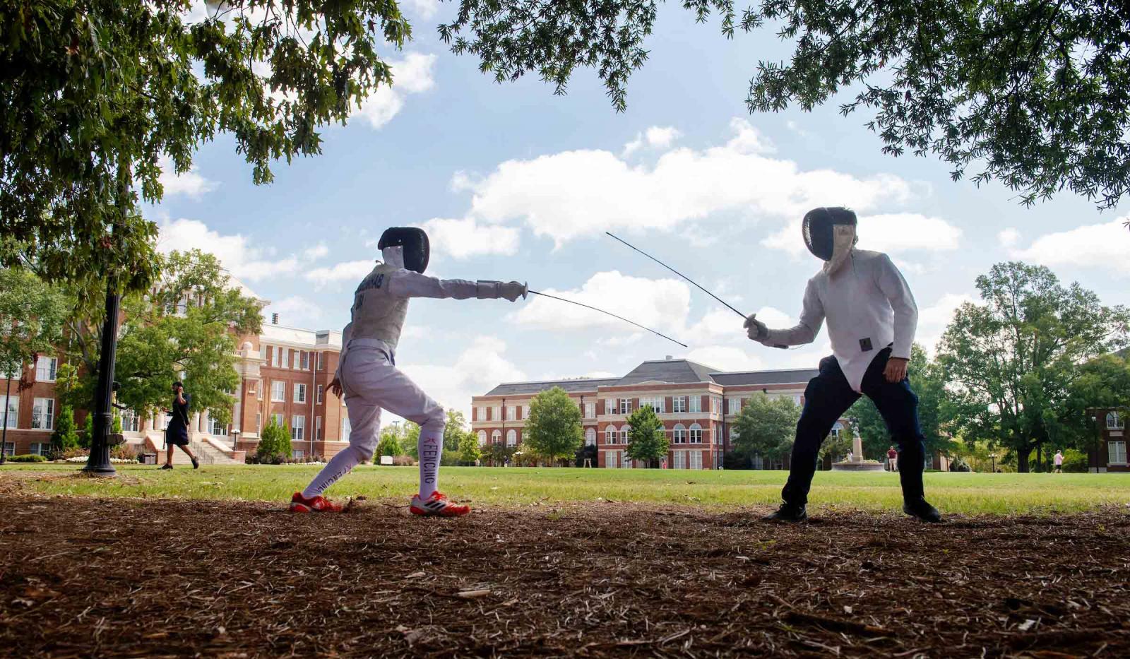 Two Dueling Dogs Fencing Club members fencing on the MSU Drill Field